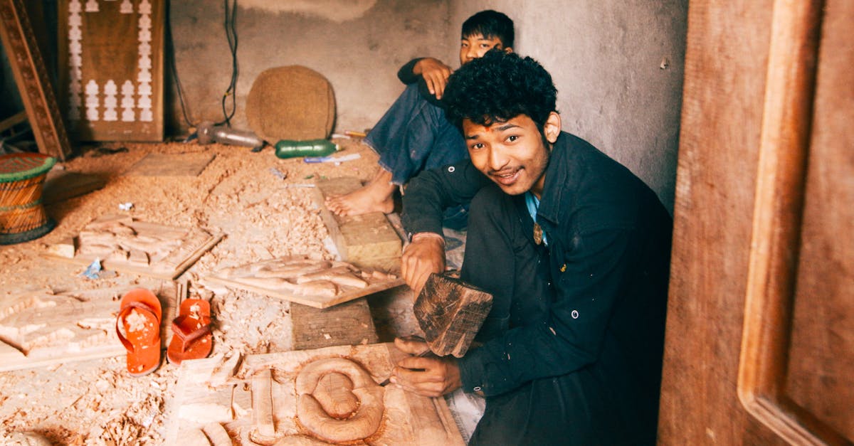 Two craftsmen working on wood carvings in a cozy workshop, surrounded by tools and wooden chips.