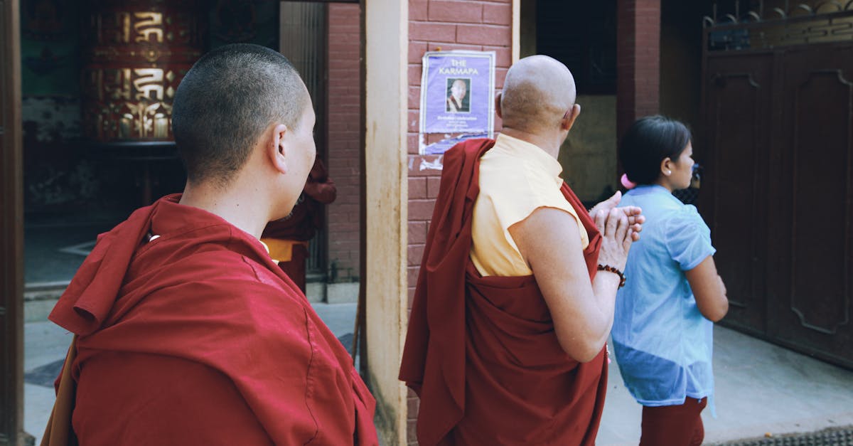 Two monks and a woman walk near a temple entrance, showcasing cultural diversity.